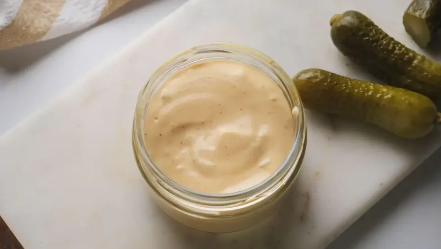 Healthy Big Mac Sauce in a Mason jar with some cucumber pickle