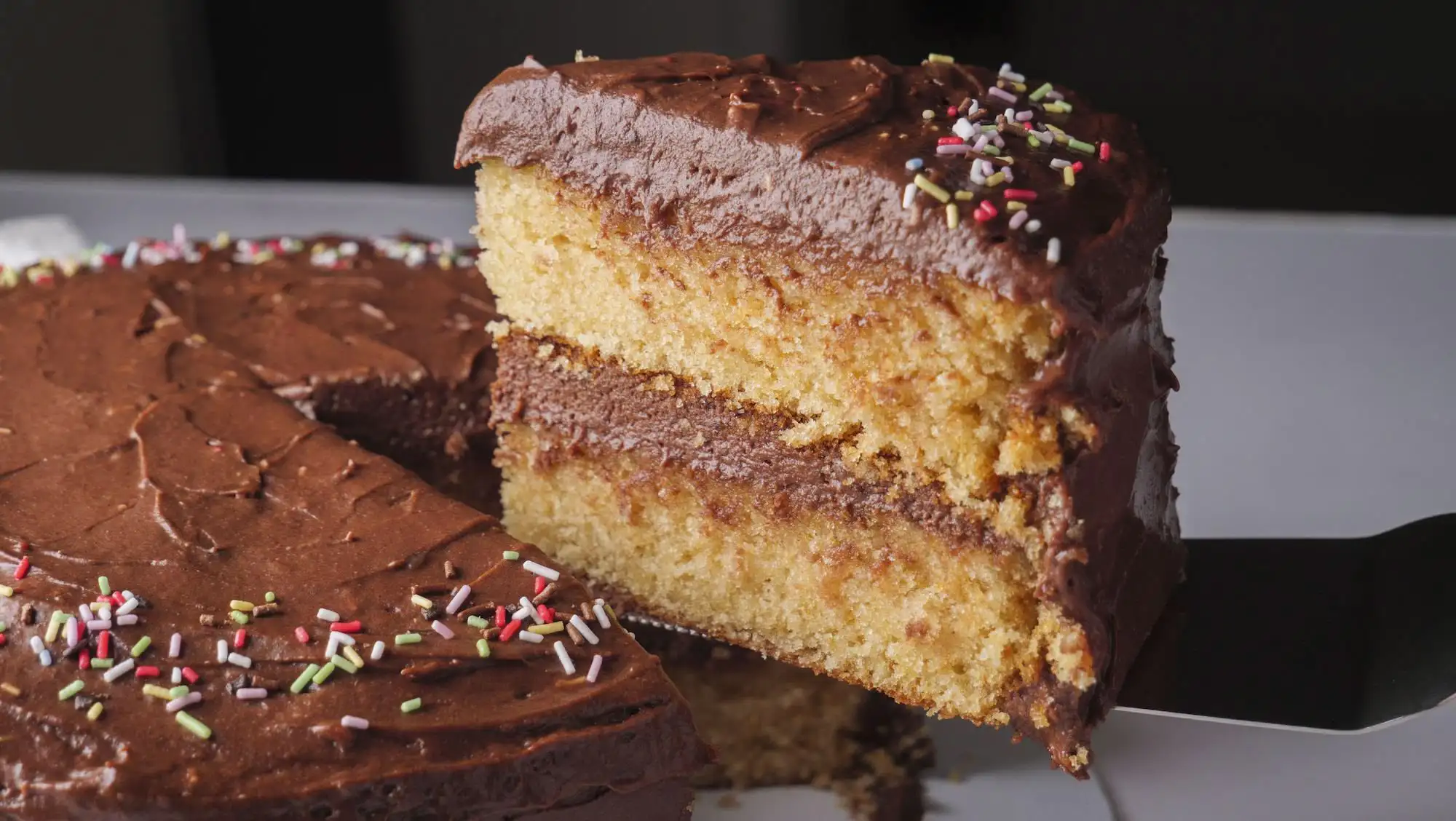 Vanilla Cake with Chocolate Frosting holding on a knife