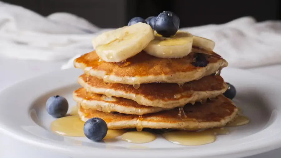 Stack of Blueberry  Banana Pancakes with banana, blueberries, and syrup.