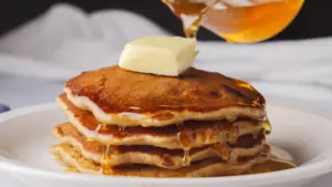 FluffyBanana Blueberry pancakes with butter and syrup on a plate.