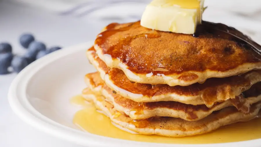 FluffyBanana Blueberry pancakes with butter and syrup on a plate.