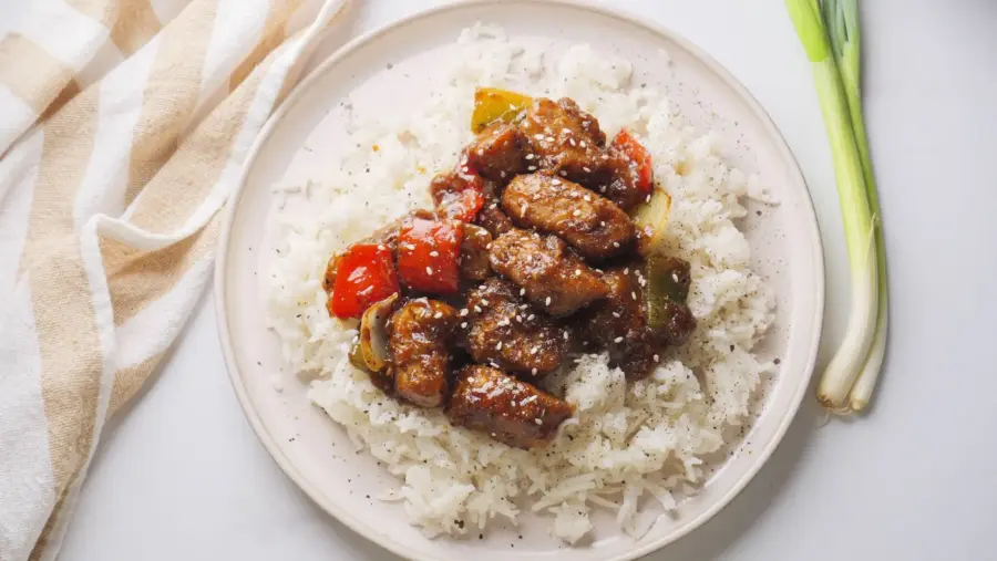 Spicy stir-fried black pepper chicken with rice and peppers on a plate.