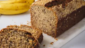 Coconut Banana bread loaf with slices on a marble board.