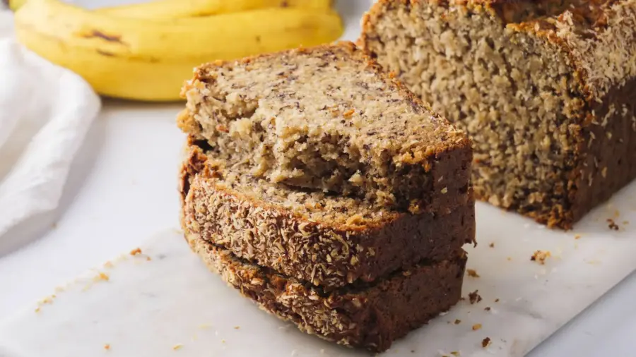 Freshly sliced coconut banana bread on a white marble surface.