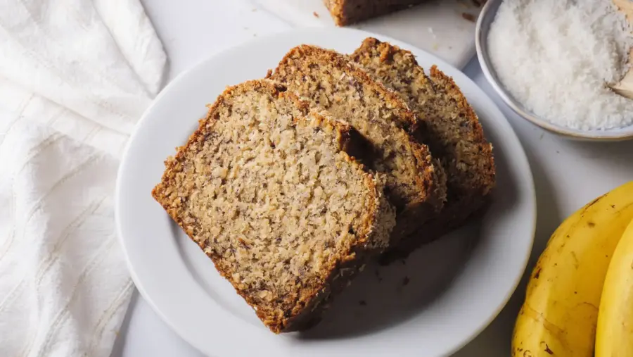 Freshly sliced coconut banana bread on a white serving plate
