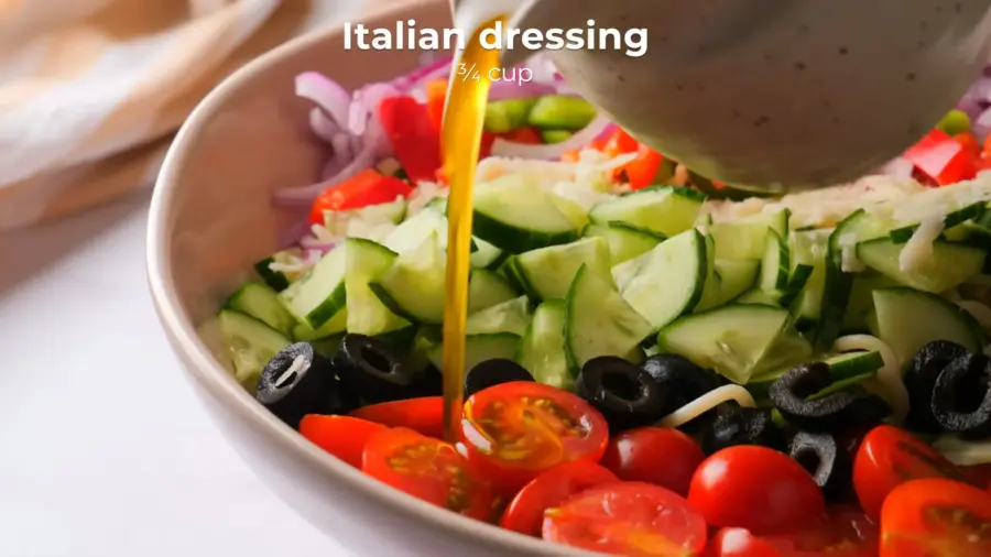 Pouring Italian dressing on fresh spaghetti salad.