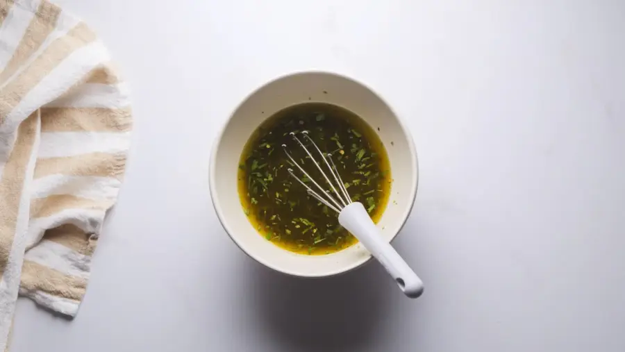 Bowl of Italian Dressing with whisk on white background.