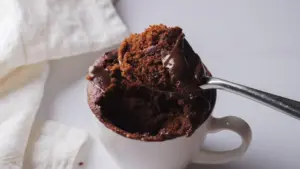 Chocolate mug cake with melting chocolate on a spoon.