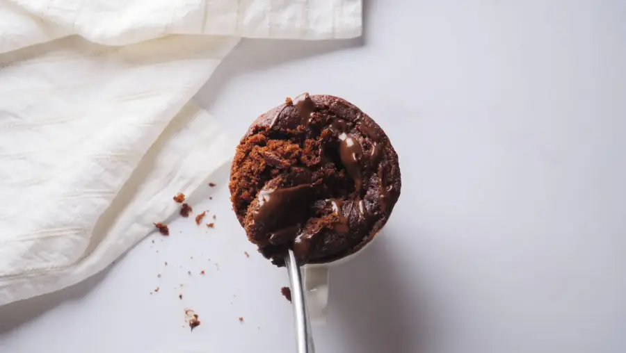 Delicious chocolate Nutella mug cake with melted chocolate and a spoon on a white background.