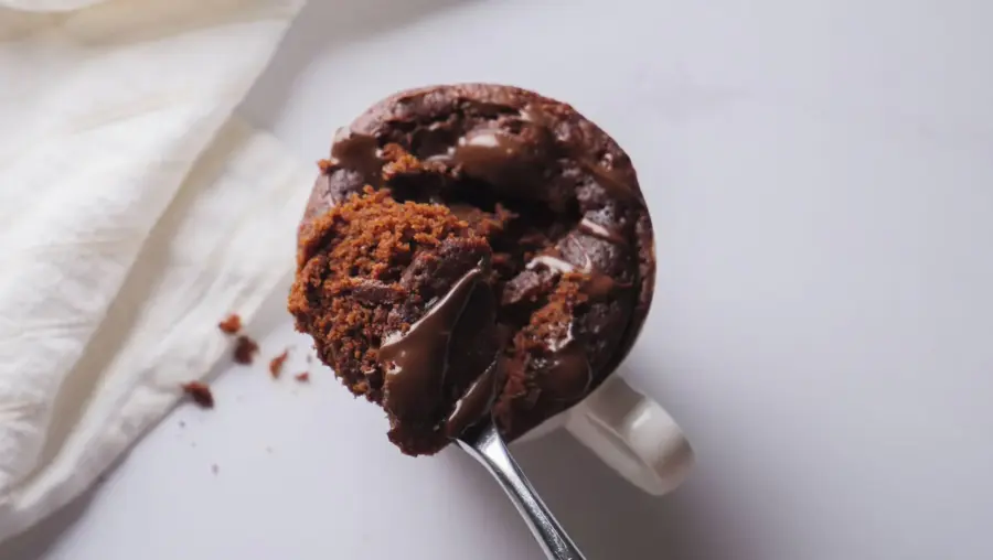 Chocolate mug cake with melting center on spoon.