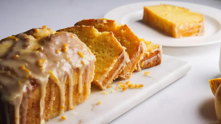 Delicious orange loaf cake with glaze on a marble board.