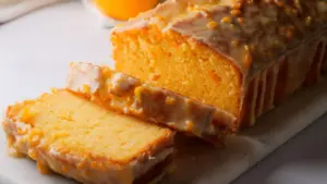Glazed orange loaf cake sliced on a marble board