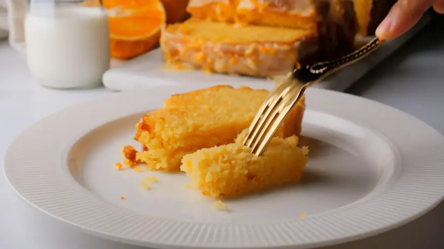 Orange loaf cake slice with a fork on a plate