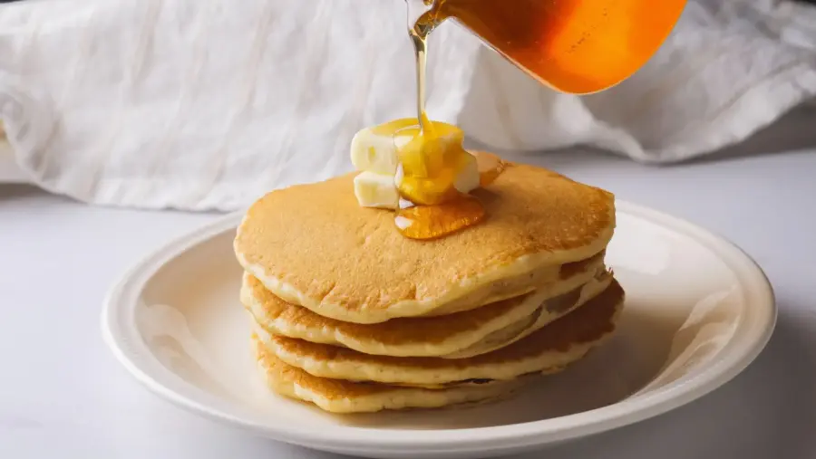 Stack of pancakes without milk, with butter and syrup drizzle.