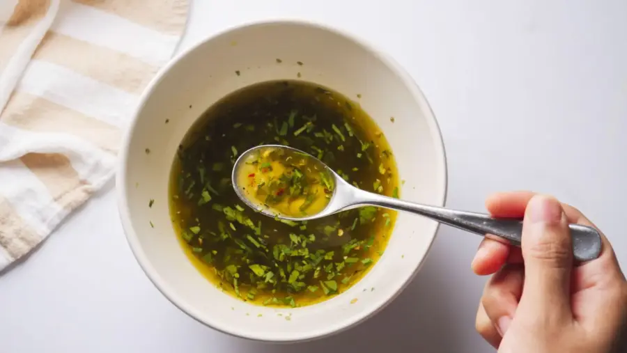  Italian dressing in a bowl with a spoon and a striped cloth.