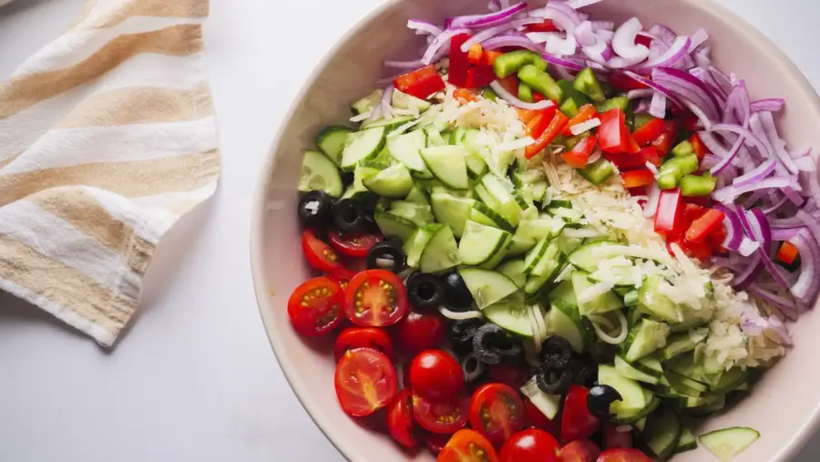 Colorful fresh vegetable salad in a bowl on top of Spaghetti