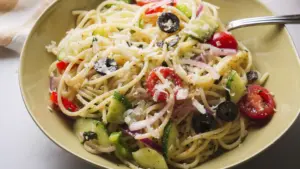 Fresh spaghetti salad with tomatoes, olives, cucumbers, bell peppers, and cheese
