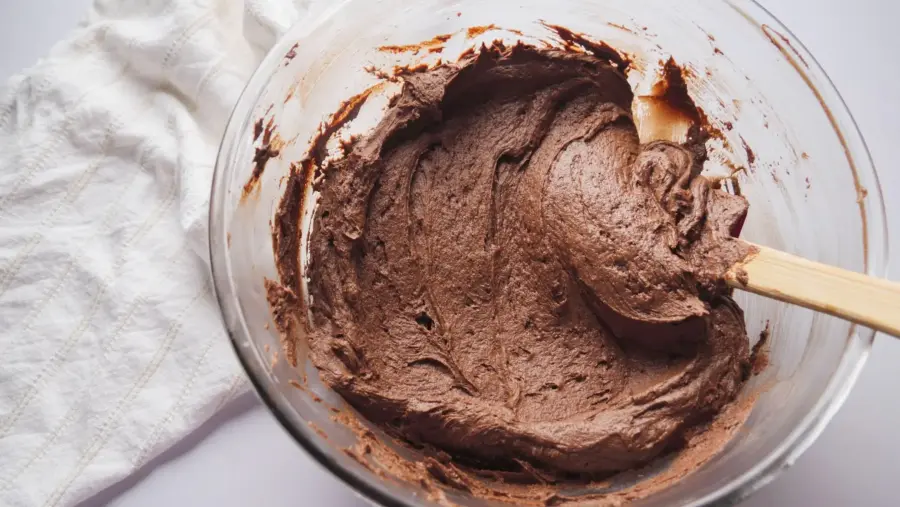 Rich chocolate cream cheese frosting in a glass bowl with a spatula.