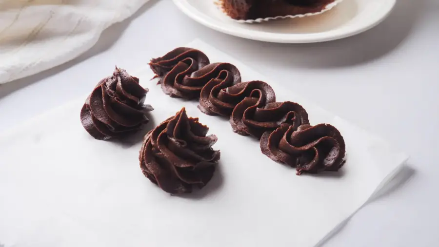 Chocolate Cream Cheese frosting dollops on white paper.