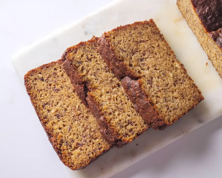 The best Almond Flour Banana Bread slices on a white marble cutting board.