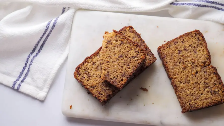 Almond Flour Banana Bread slices on a white marble cutting board.