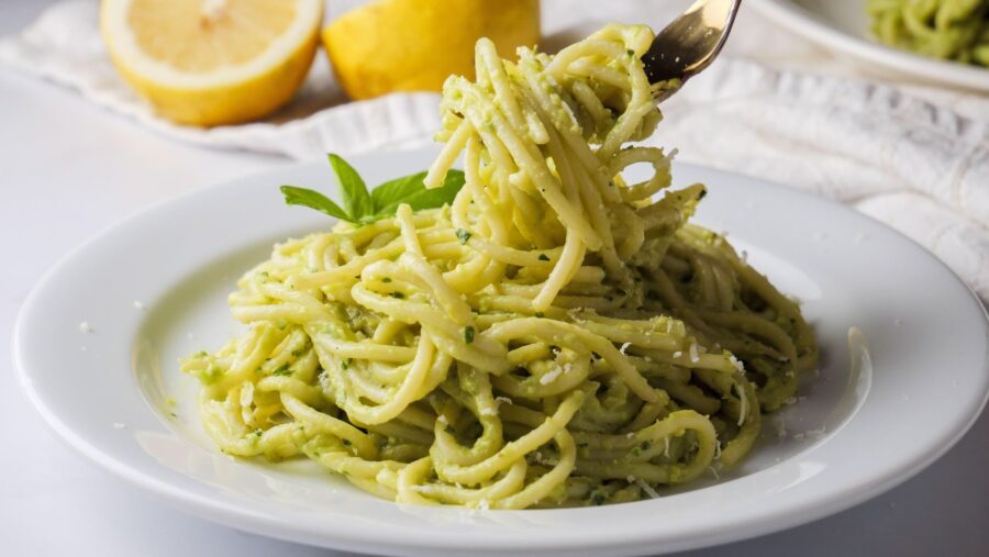 Creamy avocado pasta on a white plate with a fork