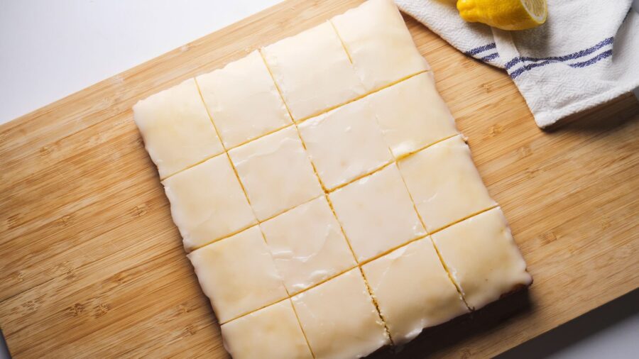 Lemon brownies with lemon icing on a wooden cutting board.