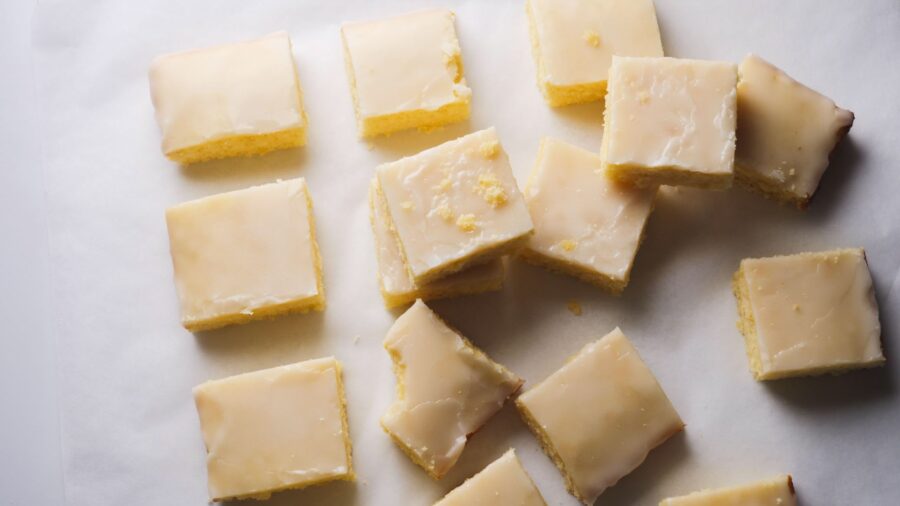 Lemon brownies with lemon glaze on parchment paper.