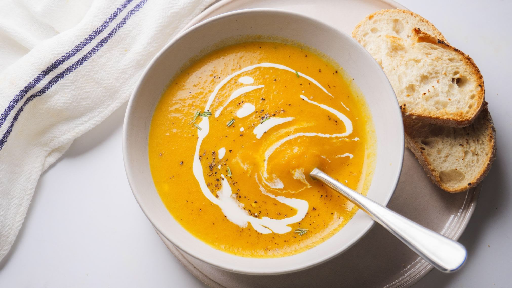 Creamy carrot soup with bread slices on the side.