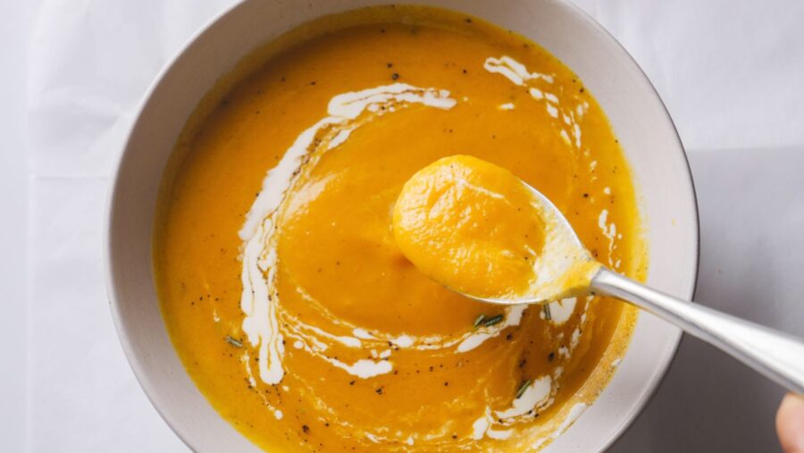Creamy carrot soup in a bowl with a spoon.