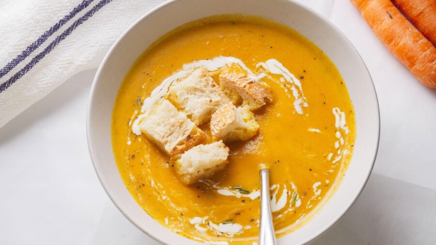 Creamy and delicious 
carrot soup with croutons in a white bowl.