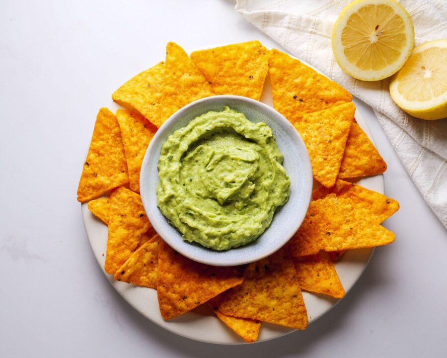 Creamy Avocado Sauce with Nachos garnished with lemon slices.