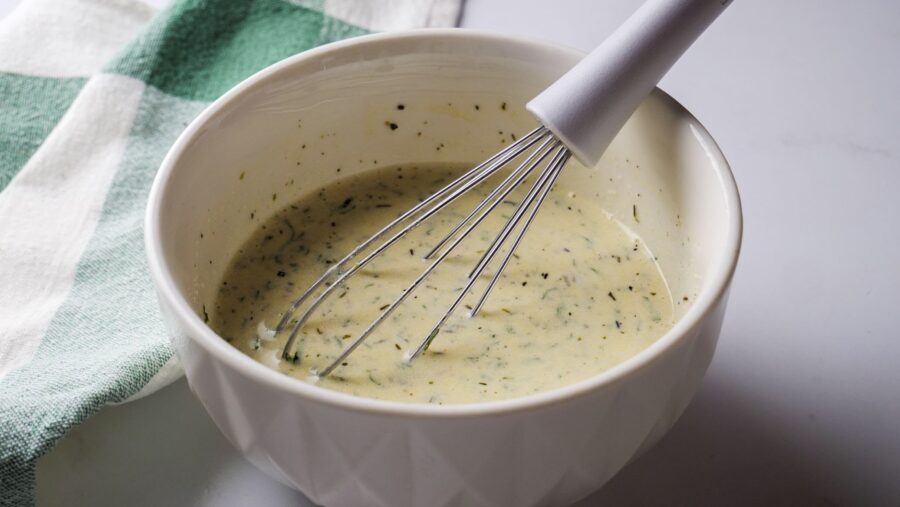 Creamy Italian dressing in a bowl with a whisk nearby.