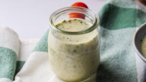 Creamy italian Salad dressing in a jar on a green checkered cloth.