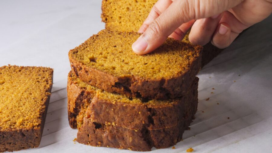 Hand holding slice of freshly baked pumpkin bread