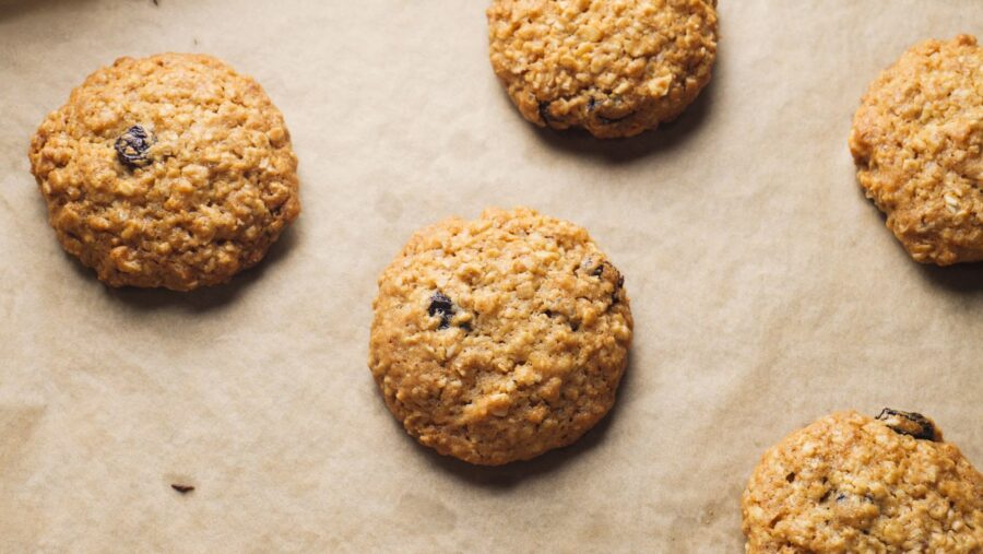 Oatmeal cookies with raisins and walnuts on parchment paper.