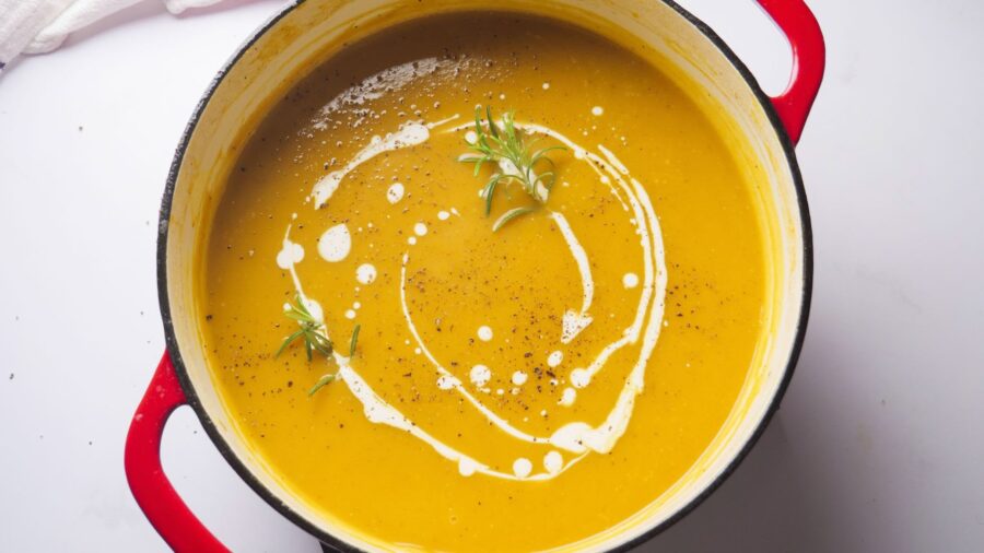 Homemade butternut squash soup garnished with herbs and spices in a dutch oven