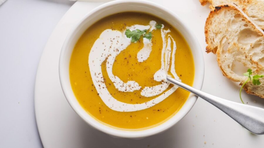 Creamy butternut squash soup with cilantro and bread on the side.