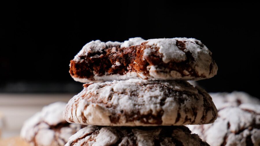Chocolate crinkle cookies stacked with a bite taken.