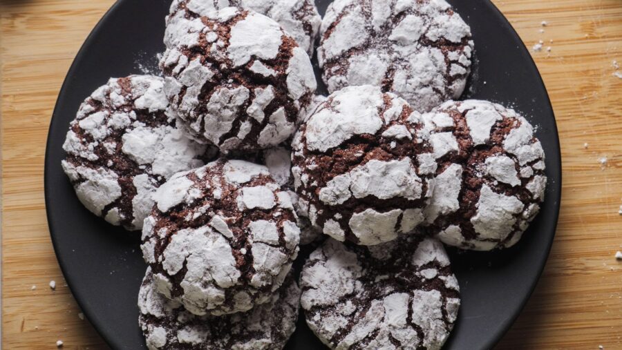 Chocolate crinkle cookies with powdered sugar on a black plate