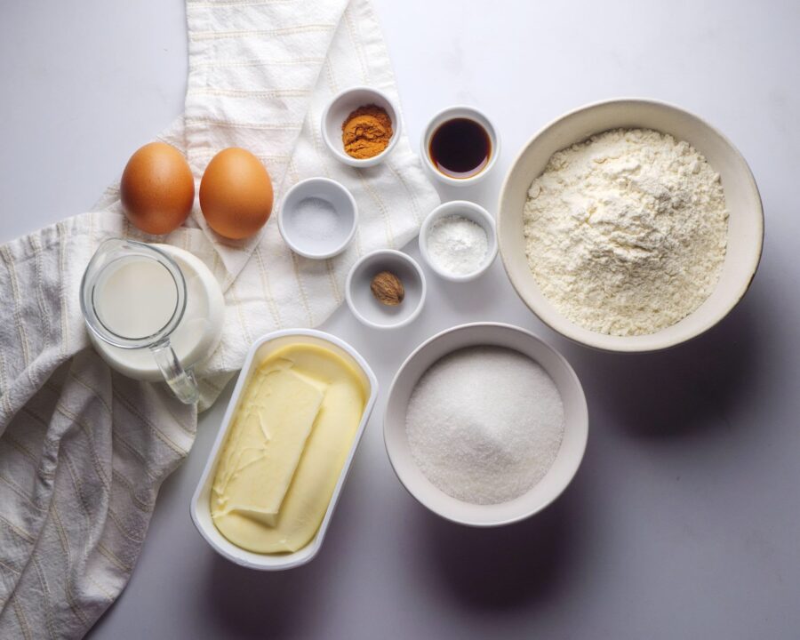 Baking ingredients: flour, sugar, eggs, butter, milk, spices.