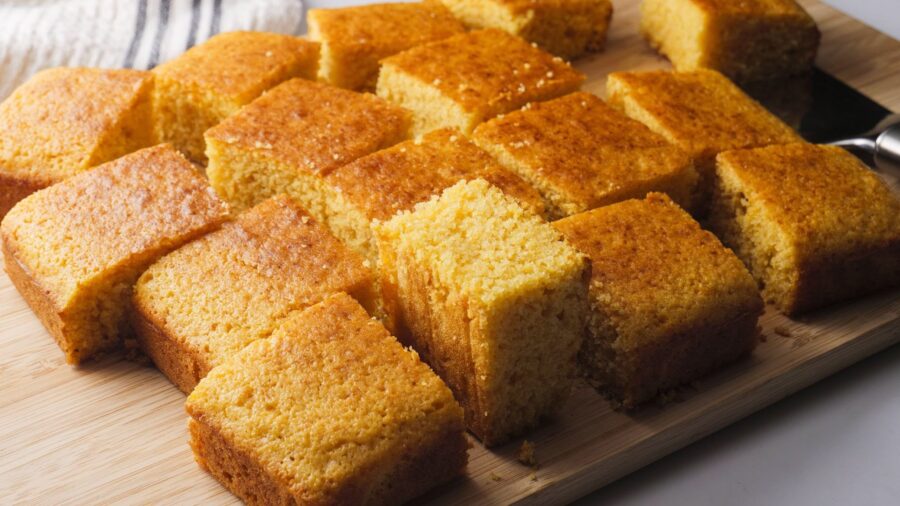 Golden cornbread squares on a wooden board.