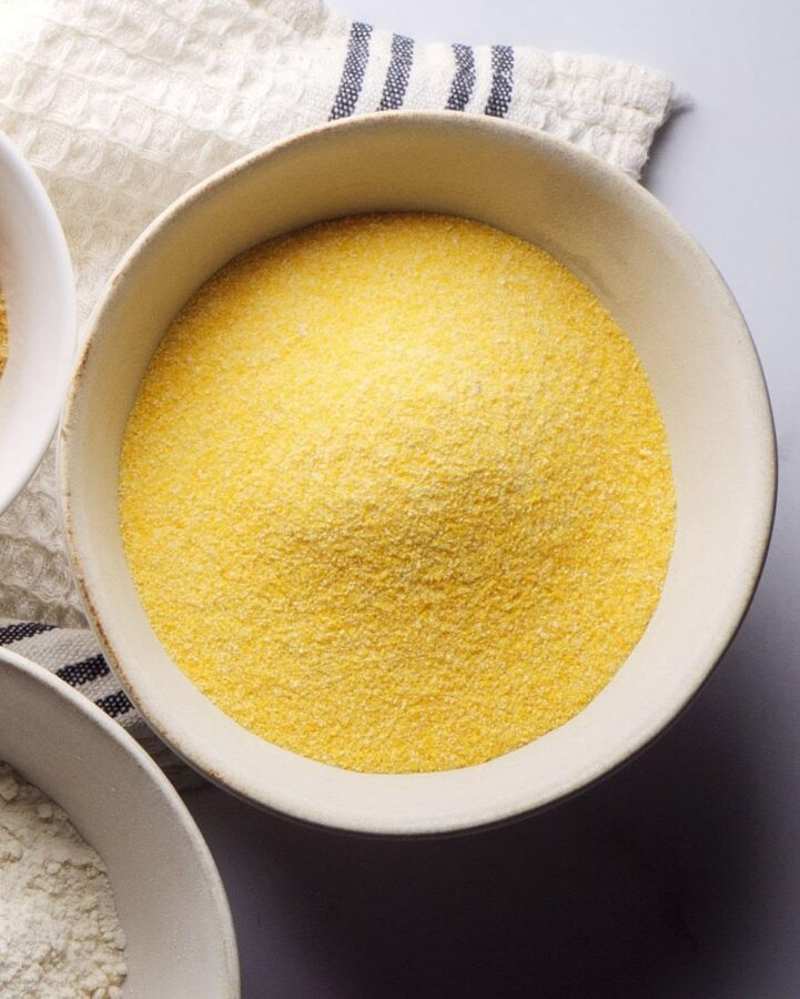 Bowl of yellow cornmeal on a checkered cloth background.