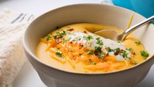 Creamy Potato Soup topped with herbs, cheddar cheese, and yogurt in a bowl.