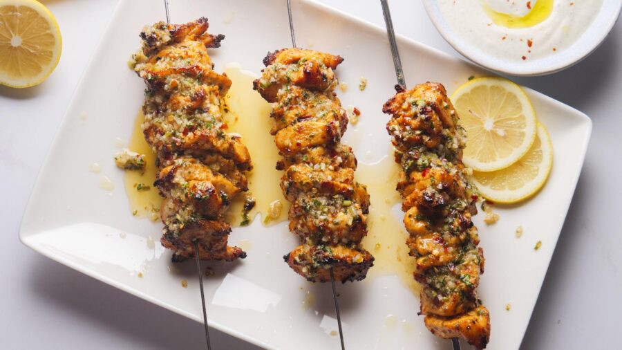 Grilled chicken skewers with herbs and lemon slices.