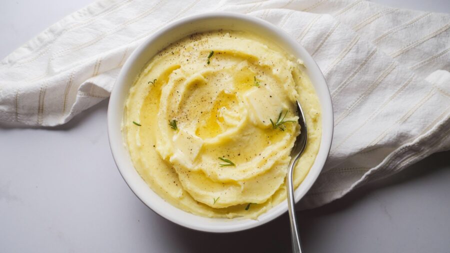 Creamy and buttery garlic mashed potatoes with butter and herbs in a bowl.
