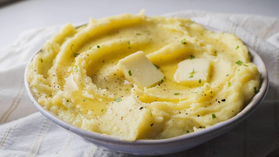 Buttery mashed potatoes with garlic, butter, and herbs in a bowl.