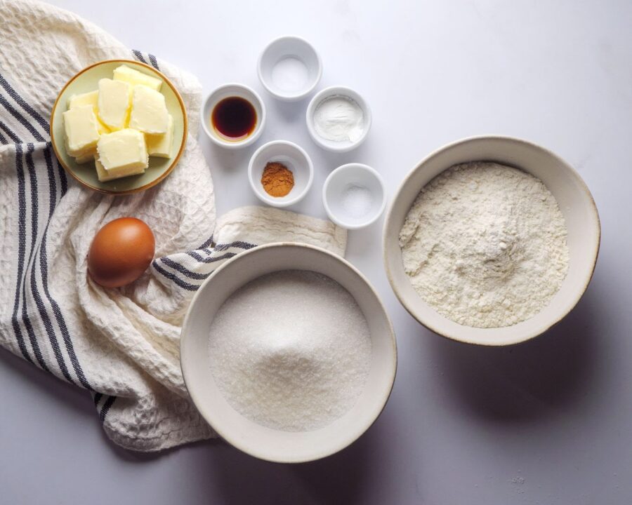 Baking ingredients: butter, flour, sugar, egg, spices, and bowls.