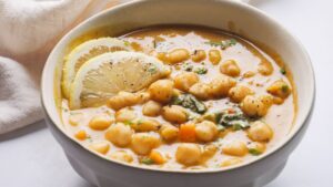 Lemon Chickpea soup with lemon slices in white bowl.