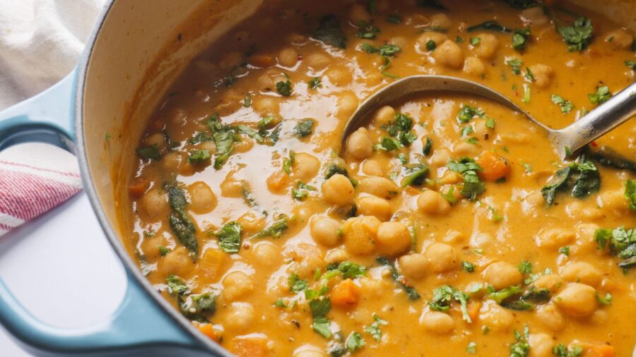 Hearty lemony chickpea soup in a pot with fresh herbs and spinach